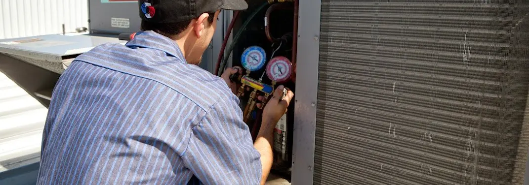 HVAC technician servicing a condenser unit in East Stroudsburg